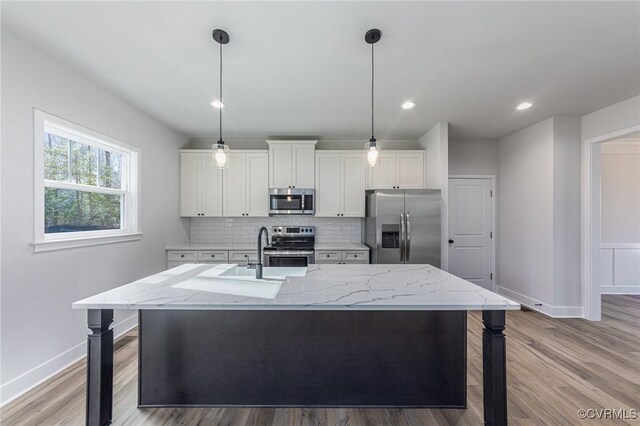 kitchen featuring white cabinets, light hardwood / wood-style flooring, an island with sink, and stainless steel appliances