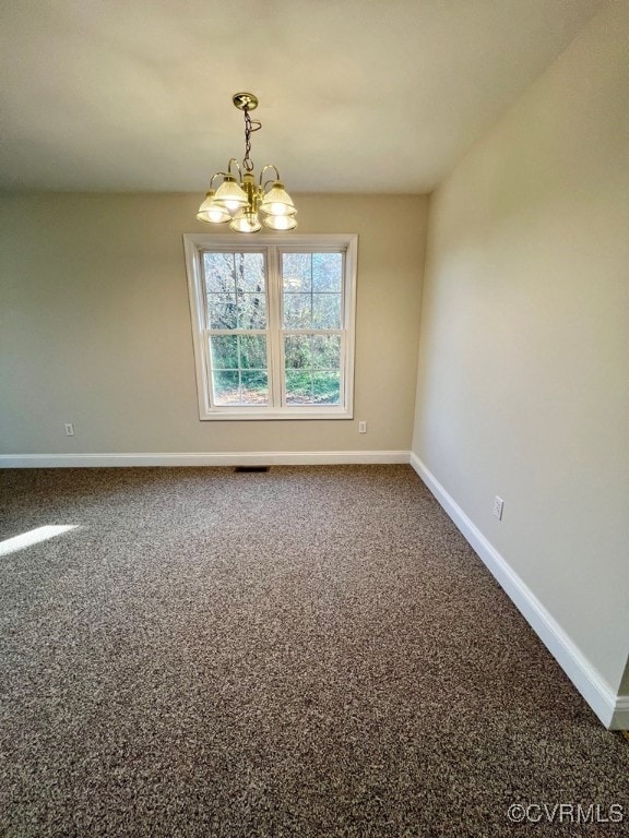 carpeted empty room with an inviting chandelier