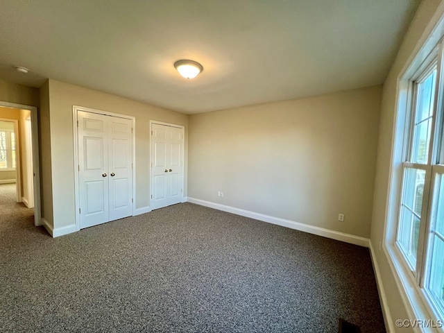 unfurnished bedroom featuring carpet floors, two closets, and multiple windows