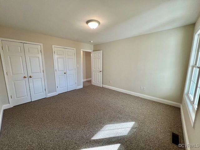 unfurnished bedroom with carpet and two closets