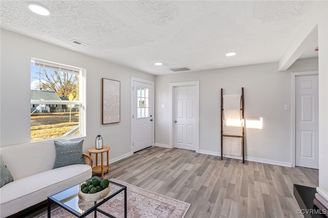 living room with light wood-type flooring and a textured ceiling