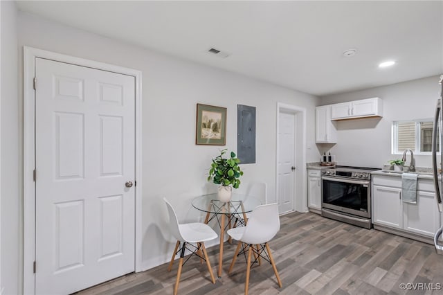 kitchen featuring electric panel, white cabinetry, stainless steel electric range, and hardwood / wood-style flooring