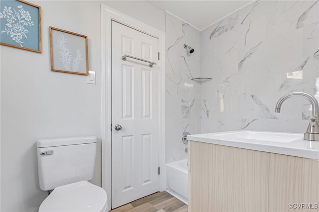 full bathroom with vanity, toilet, tiled shower / bath, and hardwood / wood-style flooring