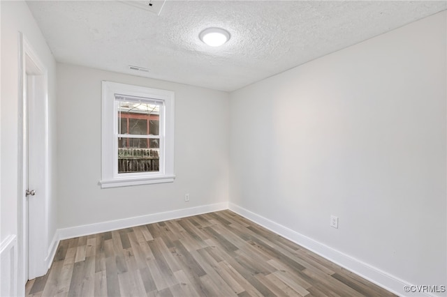 unfurnished room with hardwood / wood-style floors and a textured ceiling