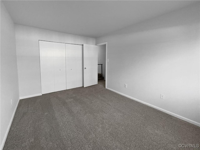 unfurnished bedroom featuring dark colored carpet and a closet