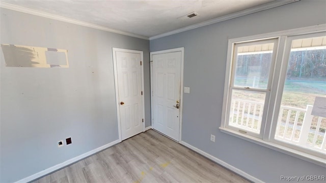 unfurnished room featuring a healthy amount of sunlight, ornamental molding, and light hardwood / wood-style flooring