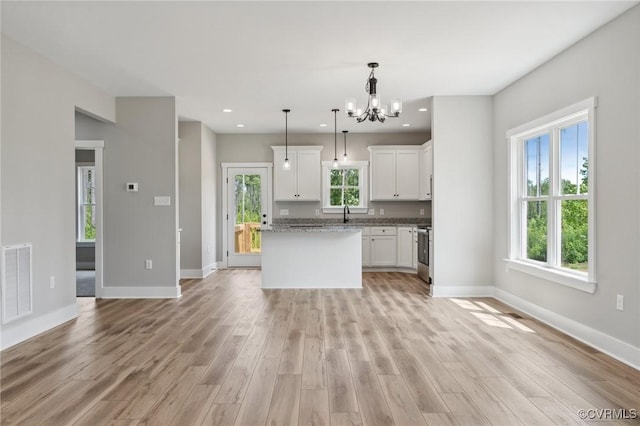 kitchen featuring pendant lighting, a healthy amount of sunlight, light wood-type flooring, and white cabinetry