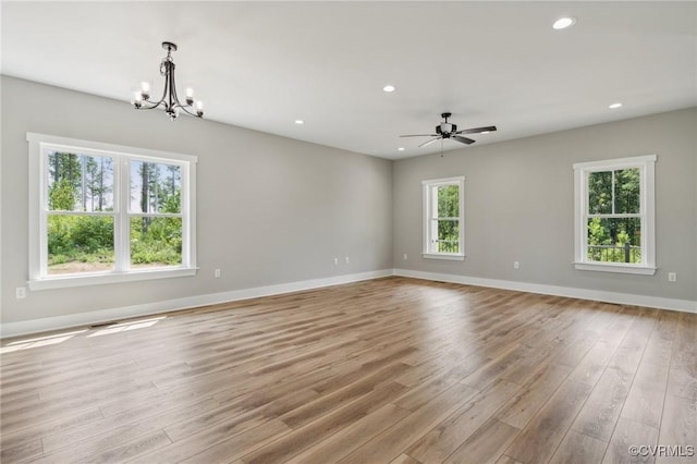 unfurnished room with light hardwood / wood-style flooring and ceiling fan with notable chandelier