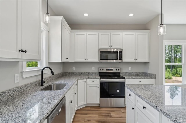 kitchen featuring pendant lighting, stainless steel appliances, white cabinetry, and sink