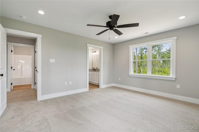 unfurnished bedroom featuring ceiling fan, light colored carpet, and connected bathroom