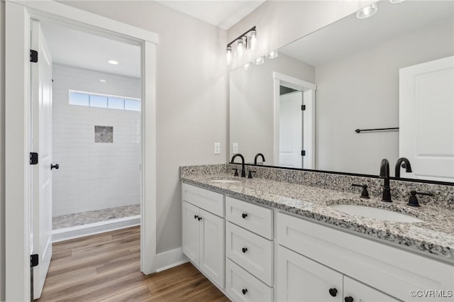 bathroom featuring tiled shower, hardwood / wood-style floors, and vanity