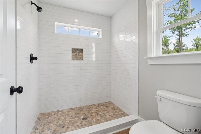 bathroom featuring tiled shower and toilet