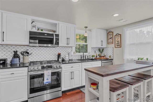 kitchen featuring white cabinetry, sink, hanging light fixtures, a kitchen breakfast bar, and appliances with stainless steel finishes