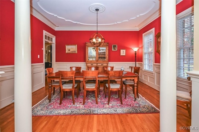 dining area featuring decorative columns, wood finished floors, and crown molding