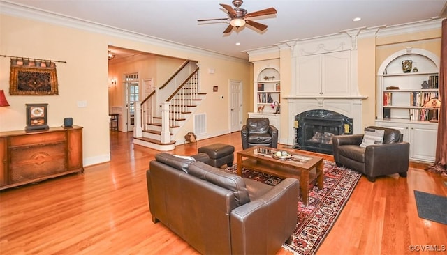 living area with built in features, light wood finished floors, and ceiling fan