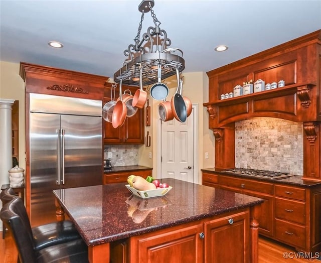 kitchen with open shelves, dark stone countertops, a kitchen island, backsplash, and stainless steel appliances