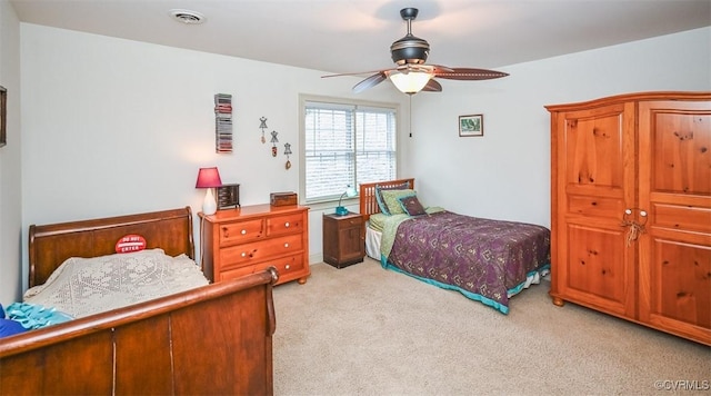 bedroom with visible vents, light colored carpet, and a ceiling fan