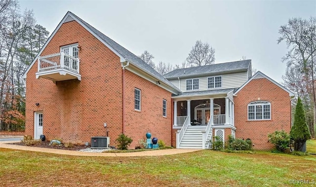 exterior space with a balcony, covered porch, a front lawn, french doors, and brick siding