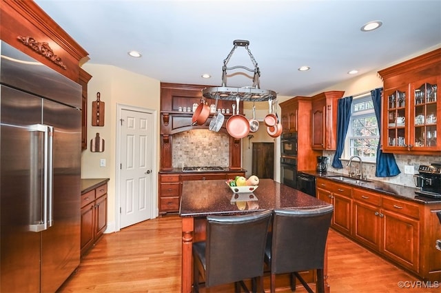 kitchen with a sink, tasteful backsplash, appliances with stainless steel finishes, and light wood-style flooring