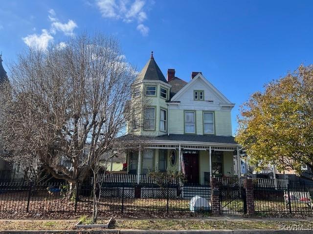 victorian house with a porch and a fenced front yard