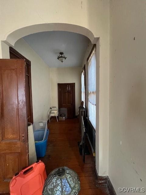 hallway with arched walkways and wood finished floors