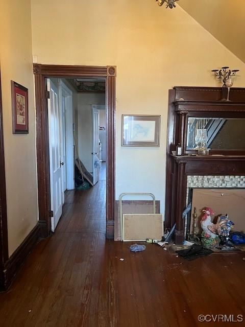 hall featuring lofted ceiling, wood finished floors, and baseboards