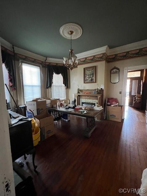 dining area with ornamental molding, a fireplace, wood finished floors, and a notable chandelier