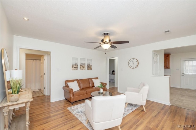 living room featuring a textured ceiling, light hardwood / wood-style floors, and ceiling fan