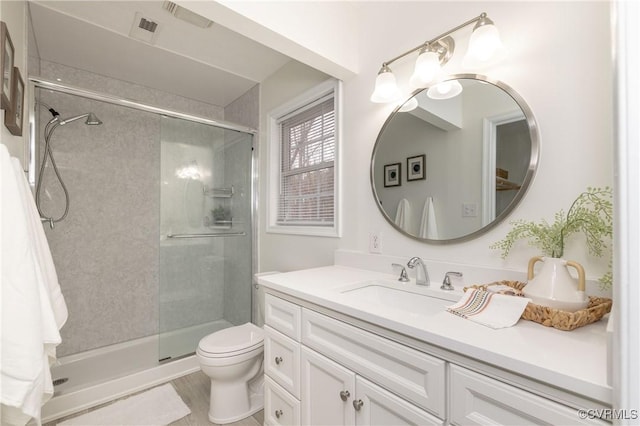 bathroom featuring vanity, toilet, and a shower with door