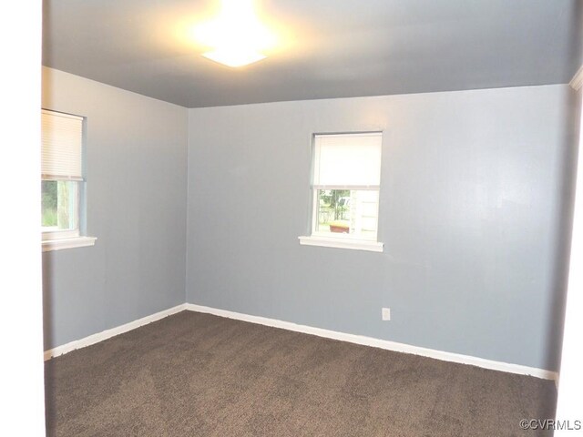 spare room with dark colored carpet and baseboards