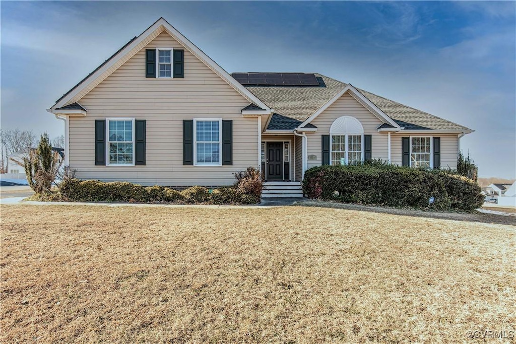 view of front of home featuring a front lawn and solar panels