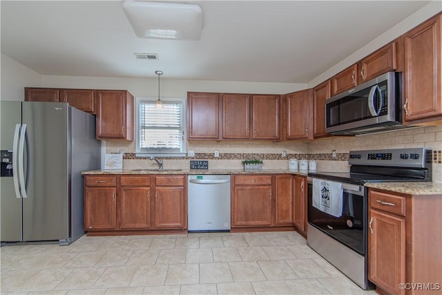 kitchen with sink, backsplash, hanging light fixtures, stainless steel appliances, and light stone countertops