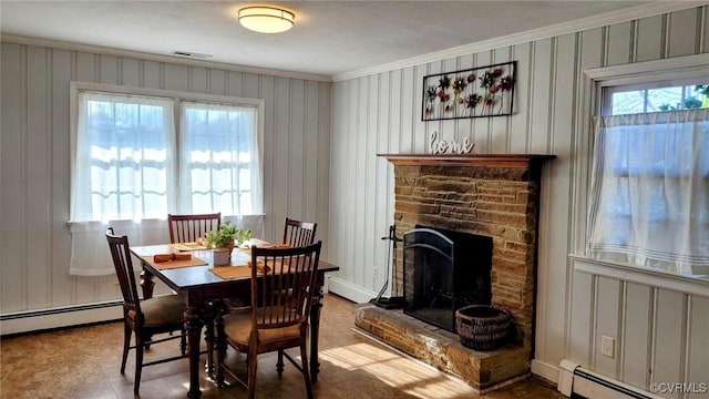 dining area with a fireplace with raised hearth, baseboard heating, and ornamental molding