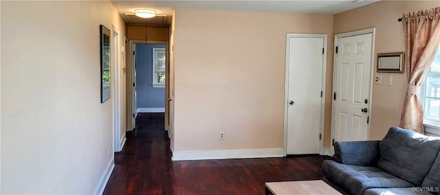 unfurnished living room featuring attic access, wood finished floors, and baseboards