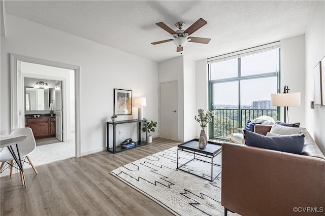 living room with ceiling fan, a textured ceiling, and light wood-type flooring