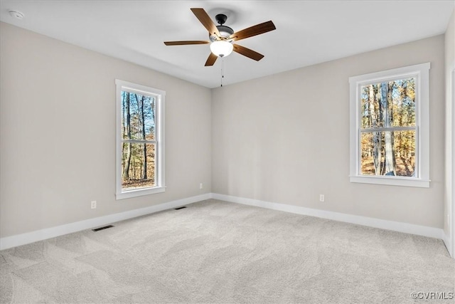 spare room featuring a healthy amount of sunlight, light colored carpet, and ceiling fan