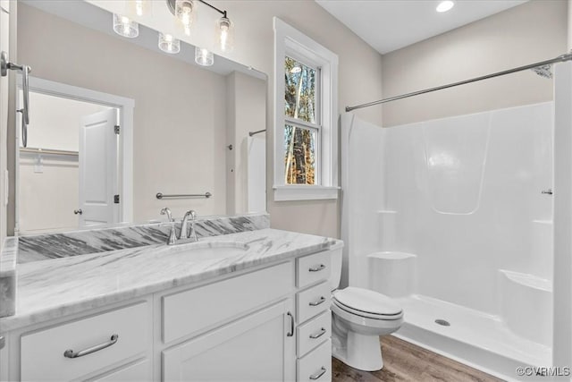 bathroom with walk in shower, vanity, toilet, and hardwood / wood-style floors