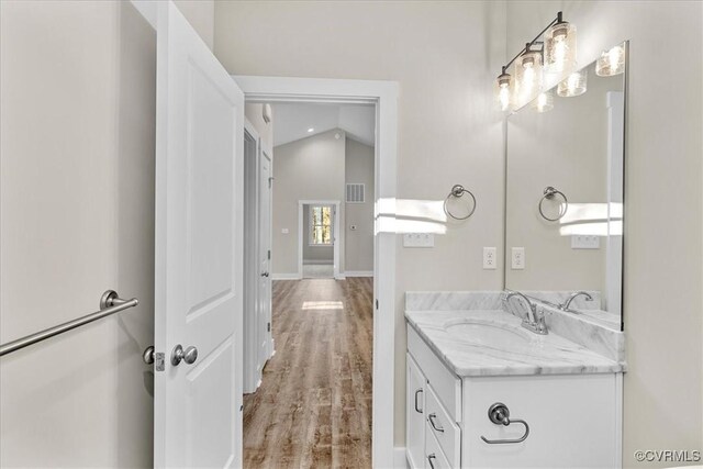 bathroom featuring wood-type flooring, lofted ceiling, and vanity