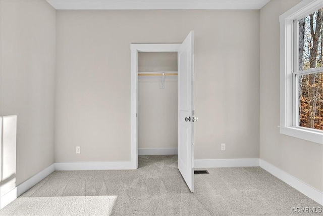 unfurnished bedroom featuring multiple windows, light carpet, and a closet