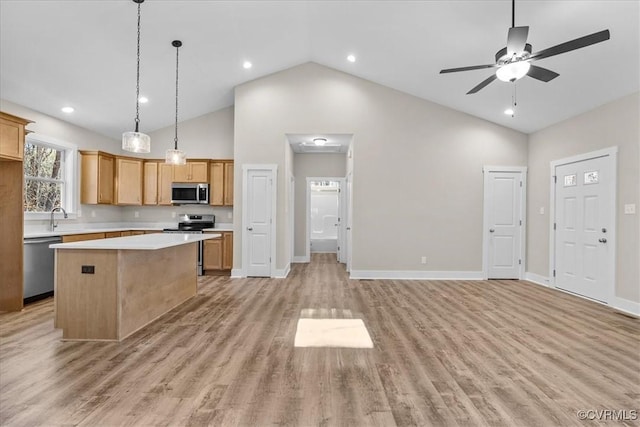 kitchen featuring stainless steel appliances, hanging light fixtures, a kitchen island, and light wood-type flooring