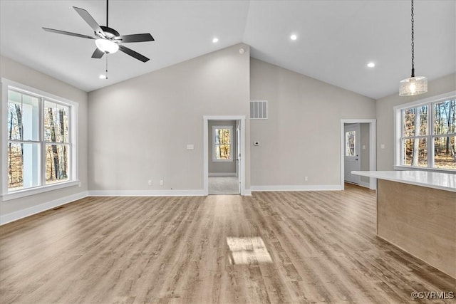 unfurnished living room with ceiling fan, high vaulted ceiling, and light hardwood / wood-style floors