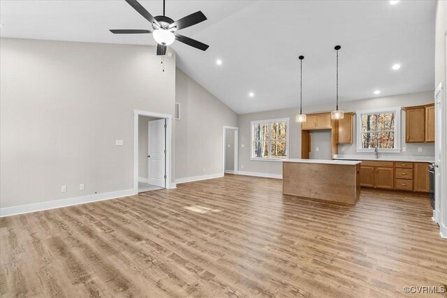 kitchen featuring pendant lighting, ceiling fan, high vaulted ceiling, a center island, and light wood-type flooring