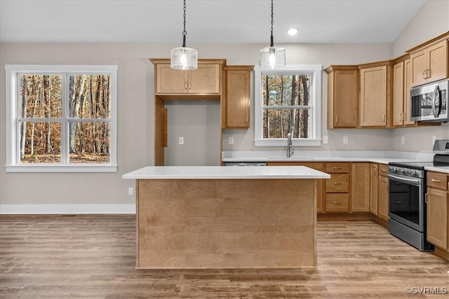 kitchen featuring a kitchen island, decorative light fixtures, sink, light hardwood / wood-style floors, and stainless steel appliances