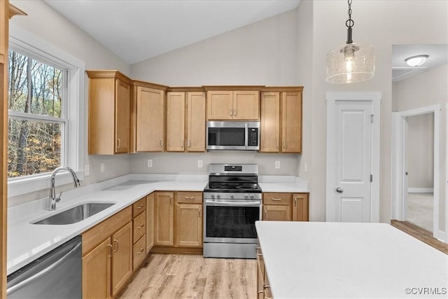 kitchen with hanging light fixtures, vaulted ceiling, appliances with stainless steel finishes, and sink