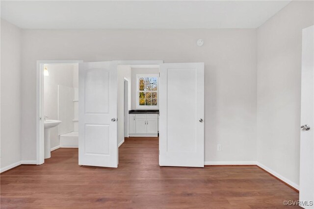 unfurnished bedroom featuring hardwood / wood-style flooring and ensuite bathroom