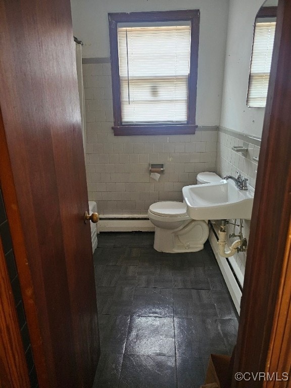 bathroom with toilet, sink, tile walls, and a baseboard radiator