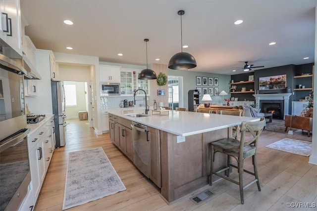 kitchen featuring a spacious island, sink, decorative light fixtures, stainless steel appliances, and white cabinets