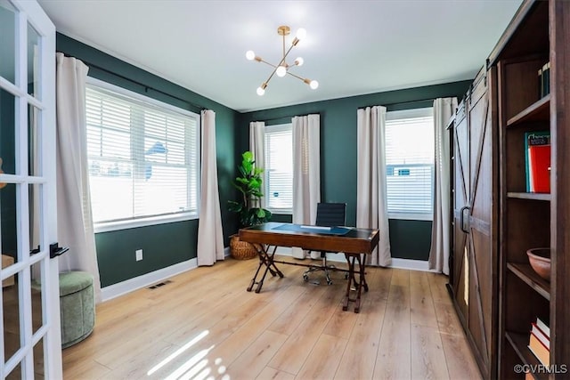 home office featuring a notable chandelier, a healthy amount of sunlight, and light wood-type flooring