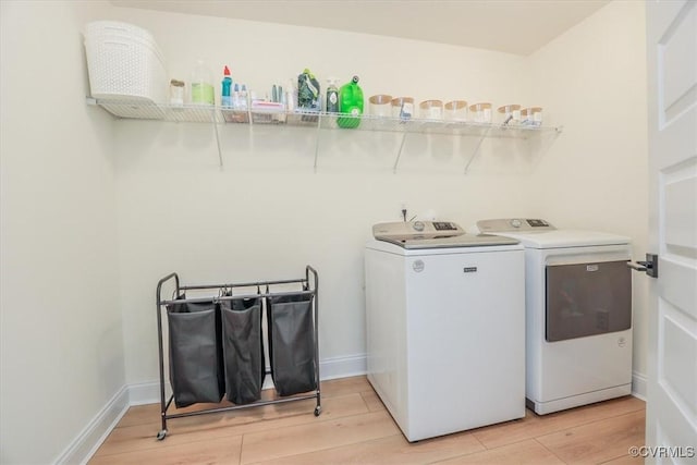 laundry room with separate washer and dryer and light hardwood / wood-style flooring