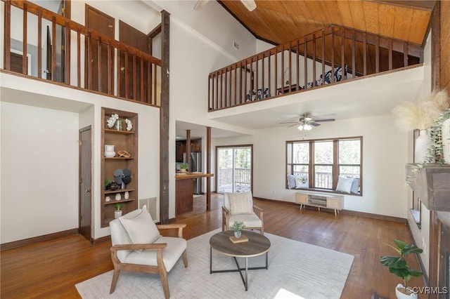 living room featuring ceiling fan, a towering ceiling, dark wood-type flooring, and wood ceiling